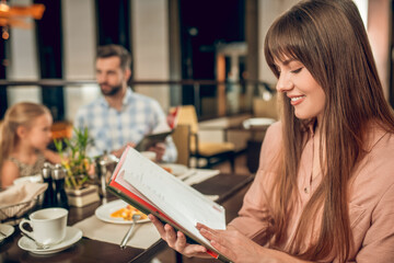 Young woman holding a menu and choosing what to order