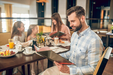 Young man holding a menu and choosing what to order