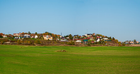 Wide panoramic view of a modern cottage village in a green field.