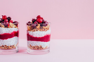 close-up of chia pudding with granola yogurt currants in a transparent glass on a pink background