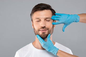 Middle-aged bearded man with closed eyes getting beauty injections