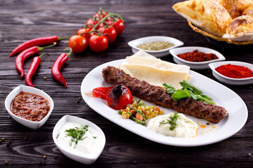 Assorted Middle Eastern and arabic dishes on a dark rustic background. Hummus, tabbouleh, pita, meat kebab, falafel, baklava. Halal food. Top view. Turkish foods, Turkish pizza, Turkish breakfast