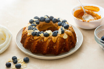 Bundt cake with peanut butter glaze. Healthy sugar gluten free cake with chia seeds decorated with blueberries and almond flakes.