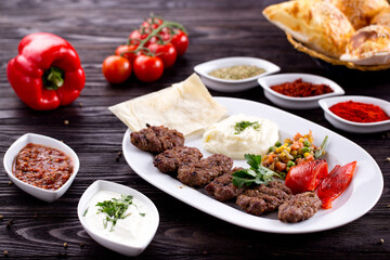 Assorted Middle Eastern and arabic dishes on a dark rustic background. Hummus, tabbouleh, pita, meat kebab, falafel, baklava. Halal food. Top view. Turkish foods, Turkish pizza, Turkish breakfast
