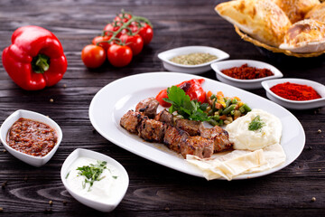 Assorted Middle Eastern and arabic dishes on a dark rustic background. Hummus, tabbouleh, pita, meat kebab, falafel, baklava. Halal food. Top view. Turkish foods, Turkish pizza, Turkish breakfast