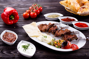 Assorted Middle Eastern and arabic dishes on a dark rustic background. Hummus, tabbouleh, pita, meat kebab, falafel, baklava. Halal food. Top view. Turkish foods, Turkish pizza, Turkish breakfast