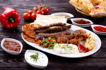 Assorted Middle Eastern and arabic dishes on a dark rustic background. Hummus, tabbouleh, pita, meat kebab, falafel, baklava. Halal food. Top view. Turkish foods, Turkish pizza, Turkish breakfast