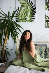 Beautiful girl is sitting on a bed closing her eyes and enjoying