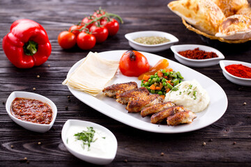 Assorted Middle Eastern and arabic dishes on a dark rustic background. Hummus, tabbouleh, pita, meat kebab, falafel, baklava. Halal food. Top view. Turkish foods, Turkish pizza, Turkish breakfast