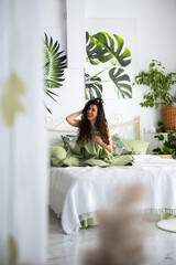 Nice woman is sitting on a bed looking on a side