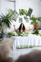 Smily woman is sitting on a bed playing with the pillows