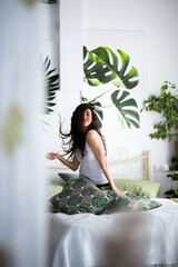 Happy woman is sitting on a bed playing with her hair