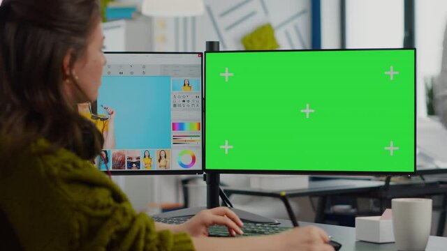Creative woman retoucher editing assets in digital retouching program, working concentrated in photo production studio looking in computer with green screen, chroma key mockup isolated display.