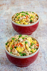 A Bowl of Asian Chicken Fried Rice with Veggies and Scrambled Eggs on Wooden Base, Vertical Photo