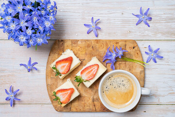 Ripe, red strawberries, pieces of pie with cottage cheese, coffee, snowdrops flowers on the table. Upper layout.