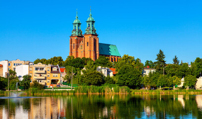 Cathedral of Virgin Mary Assumption and St. Wojciech at Lech Hill across Jelonek Lake in old town historic city center of Gniezno in Grater Poland - obrazy, fototapety, plakaty