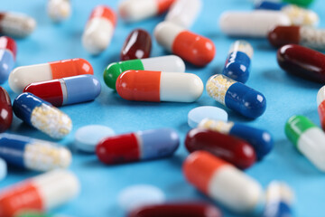 Many multicolored capsules lying on blue background closeup