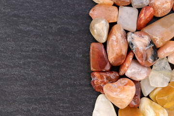 Red silk jade heap jewel stones texture on half black stone background. Place for text.