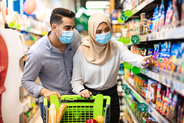 Muslim Couple Doing Grocery Shopping Choosing Organic Products In Supermarket