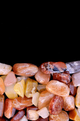 Red silk jade heap jewel stones texture on half black background. Place for text.