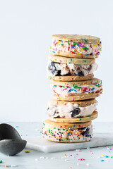Fototapeta na wymiar Close up of a stack of homemade black cherry ice cream sandwiches with sprinkles and an ice cream scoop on the side.