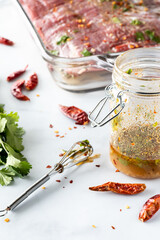 Close up view of a jar of homemade lime and cilantro marinade with a raw flank of beef in behind.