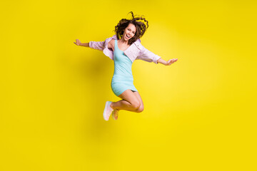 Fototapeta na wymiar Full length body size view of attractive cheerful wavy-haired girl jumping having fun life isolated over bright yellow color background