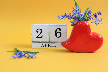 Calendar for April 26: a bouquet in a heart-shaped vase with blue flowers and numbers on cubes 26,...