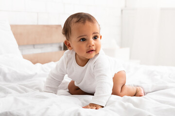 African Little Baby Crawling On Bed Looking Aside In Bedroom