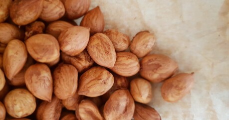 Close-up of a heap peeled whole hazelnuts, lying on crumpled paper from the top view	