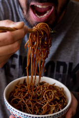 person eating a bowl of noodles