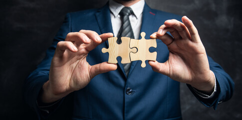 young businessman holding two puzzle pieces