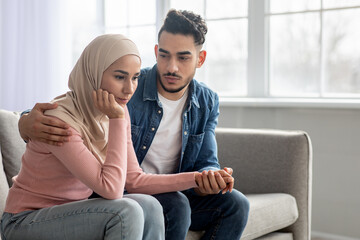 Obraz premium Loving middle-eastern man comforting his depressed wife, home interior