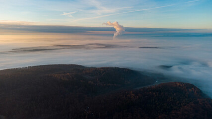 Eerie scenery of the smoke of  a factory above misty mountains