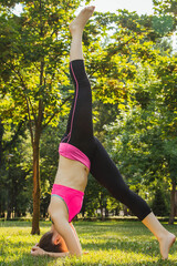 European girl in a light tracksuit doing yoga in the park in the afternoon in the summer....