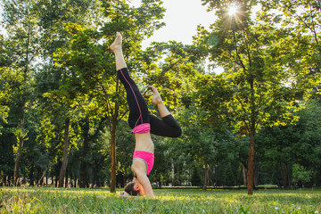 European girl in a light tracksuit doing yoga in the park in the afternoon in the summer....