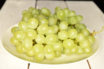 Ripe bunch of sweet grapes on a wood table, close-up.