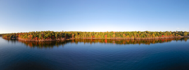 Aerial view of colorful fall forest by the fresh water lake - bright yellow, red, orange, green ...