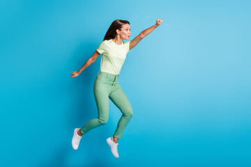 Fototapeta na wymiar Full size profile photo of optimistic brunette lady jump wear t-shirt trousers sneakers isolated on blue color background