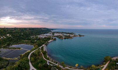 Fototapeta na wymiar Scarborough Bluffs park aerial panorama shot from above with drone, one of the Toronto city attractions. Summer day, high white clay cliffs and turquoise water of Lake Ontario. Wide angle shot.