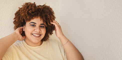 Beautiful happy smiling curvy plus size African black woman afro hair with make up posing in beige...