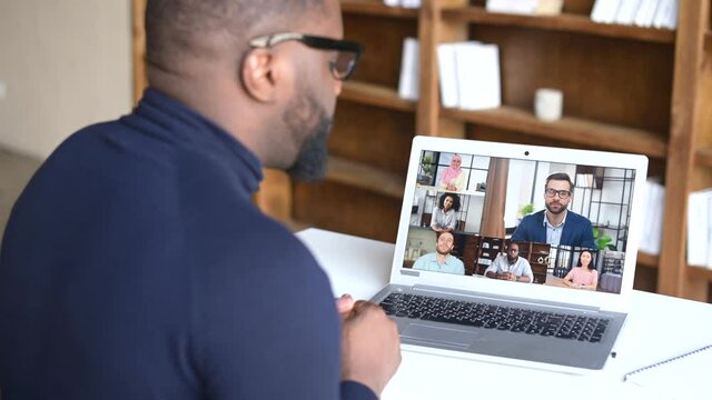 Remote meeting concept. An African-American male employee involved in video conference with group of multiracial colleagues online, diverse workteam on the laptop screen talking on the distance