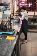 Skilled woman in chef uniform working on tasty treats