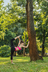 European girl in a light tracksuit doing yoga in the park in the afternoon in the summer....