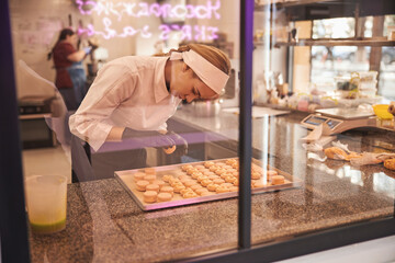 Enthusiastic pastry cook making macarons with passion and concentration