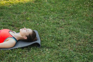 European girl in a light tracksuit doing yoga in the park in the afternoon in the summer. Gymnastics in nature. Thin woman outdoor