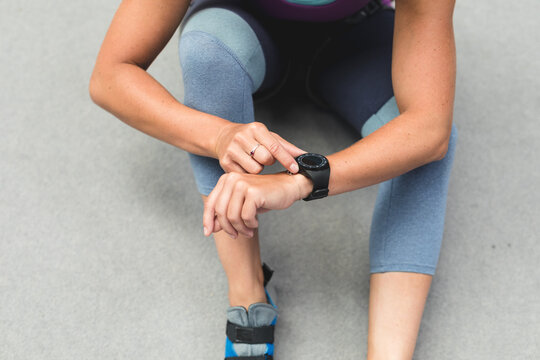 Midsection of caucasian woman checking smartwatch preparing for climb at indoor climbing wall - Powered by Adobe