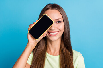 Photo of optimistic brunette lady cover eye by telephone wear light t-shirt isolated on blue color background