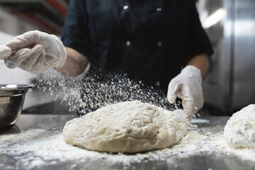 Midsection of professional chef preapring dough wearing sanitary gloves