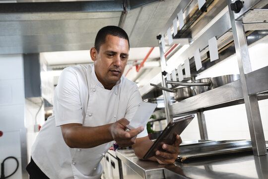 Mixed race professional chef looking at order and tablet
